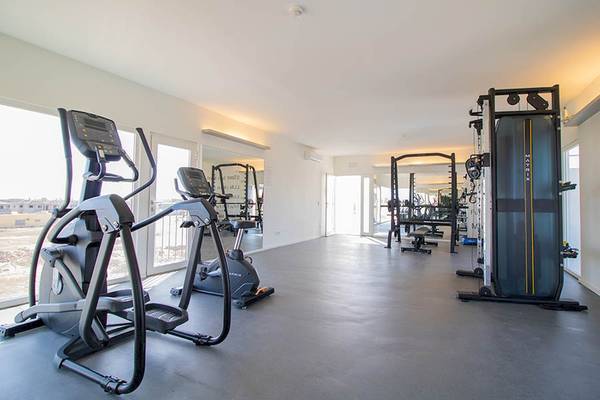 Fitnessraum im Hotel Dunas De Sal mit Geräten und Fenstern.