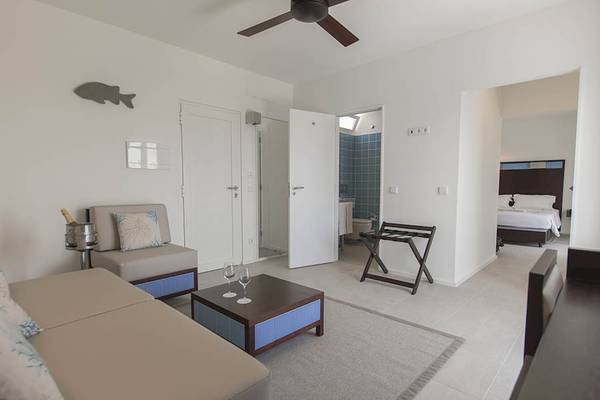 Wohnbereich des Dunas De Sal Hotels mit Sofa, Couchtisch und Weinglas.