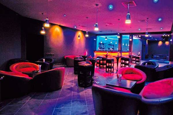Bar-Lounge im Royal Decameron Issil Resort mit rot-schwarzer Inneneinrichtung und violetten Lichtern.