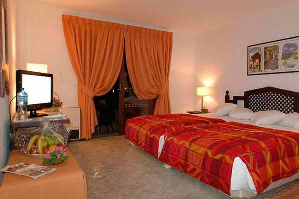 Schlafzimmer im Royal Decameron Issil Resort mit zwei Betten, Tisch, Fernseher und Lampen.