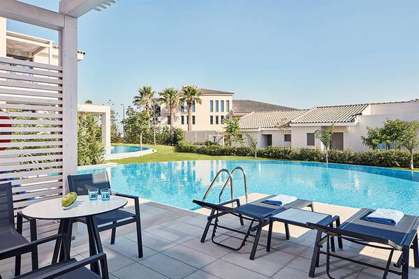 Poolbereich des Mare Ayia Napa Hotels mit Sitzecke, Tisch und Liegestühlen.