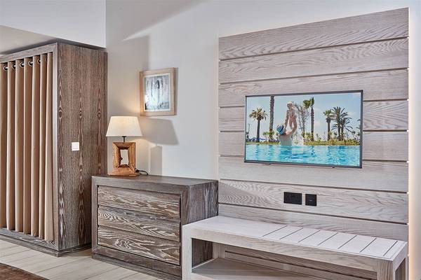 Inneneinrichtung eines Zimmers im Mare Ayia Napa Hotel mit Fernseher und Holzmöbeln.