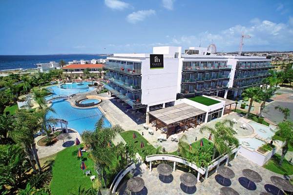 Außenansicht des Faros Hotel Ayia Napa mit Swimmingpool und Sonnenliegen.