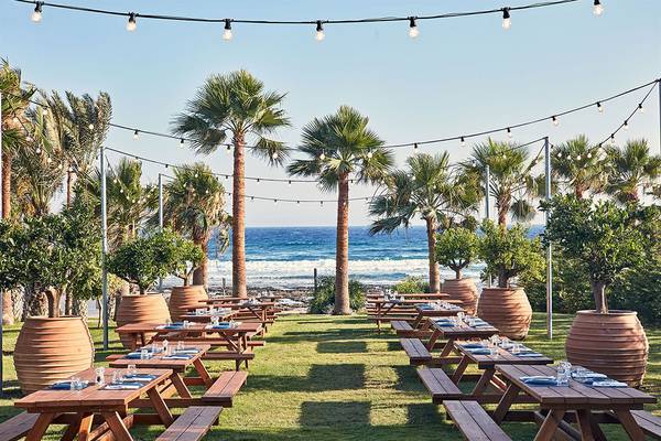 Gartenterrasse des Mare Ayia Napa Hotels mit Blick auf das Meer und abendliche Lichter.