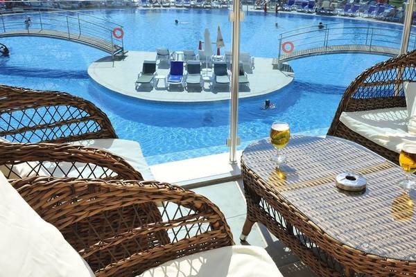 Außenbereich des Cenger Beach Resort & Spa mit Swimmingpool, Liegestühlen und Tischen.