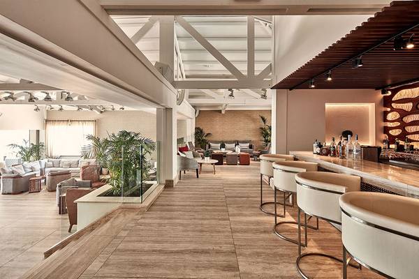 Innenansicht der Bar im Mare Ayia Napa Hotel mit Holzboden, modernen Stühlen und einer Theke.
