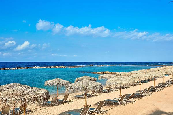 Strand des Mare Ayia Napa Hotels mit Sonnenschirmen und Liegestühlen vor blauem Meer