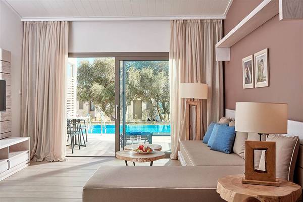 Wohnzimmer des Mare Ayia Napa Hotels mit großer Glastür, die auf einen Pool und Außenbereich führt.
