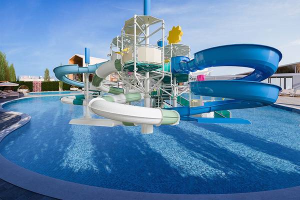 Wasserrutsche im Schwimmbad des Mare Ayia Napa Hotels, umgeben von Liegestühlen und Pflanzen.