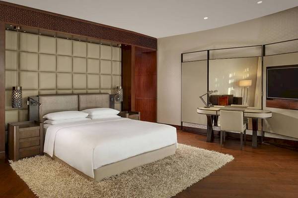 Innenansicht eines Schlafzimmers im Grand Hyatt Abu Dhabi Hotel mit Bett, Schreibtisch und Couch.