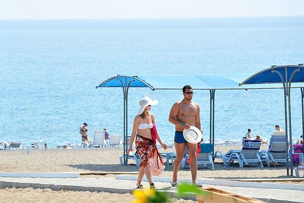 Foto von einem Strand mit dem Cenger Beach Resort & Spa im Hintergrund, wo Gäste und Personen unterwegs sind.