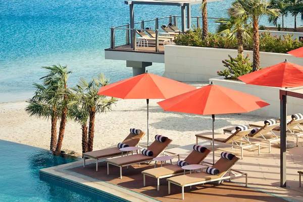 Pool-Lounge-Bereich des Grand Hyatt Abu Dhabi Hotel mit Sonnenschirmen und Liegen am Strand.