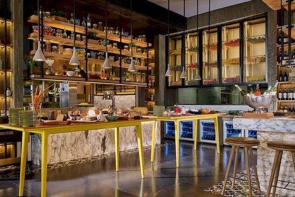 Innenbereich des Grand Hyatt Abu Dhabi Hotel mit einer Theke, gelben Tischen, Stühlen und Regalen voller Flaschen und Gläser.