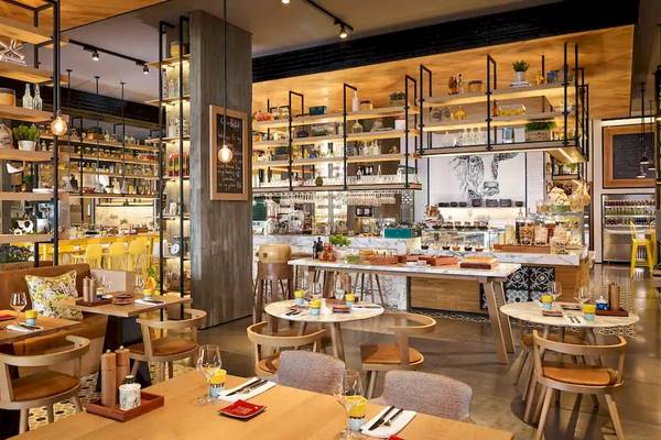 Innenbereich des Grand Hyatt Abu Dhabi Hotel Restaurants mit Holztischen, Stühlen und Regalen voller Flaschen.