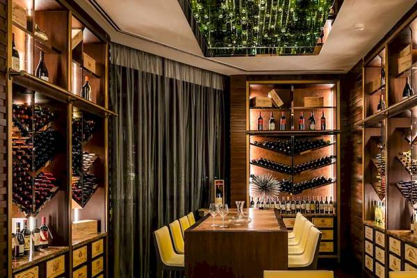 Innenansicht des Weinkellers im Grand Hyatt Abu Dhabi Hotel mit holzgetäfelten Wänden, Regalen voller Weinflaschen und einer grünen Lichtinstallation.