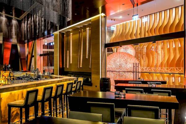 Innenbereich der Bar im Grand Hyatt Abu Dhabi Hotel mit goldenem Tresen und modernen Möbeln.