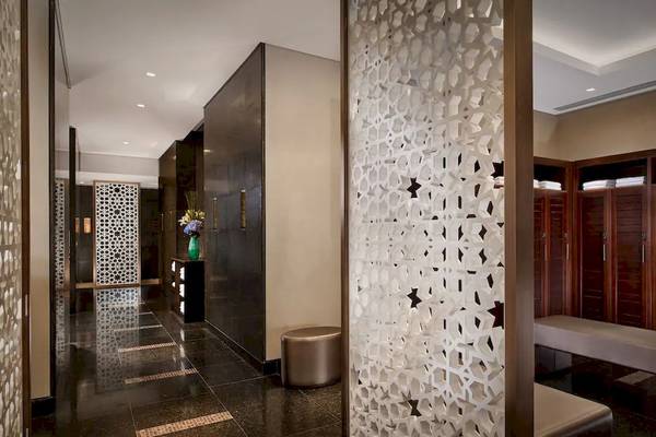 Innenbereich des Grand Hyatt Abu Dhabi Hotel mit einer gemusterten Wand, einem Tisch mit Blumen und einer Bank.