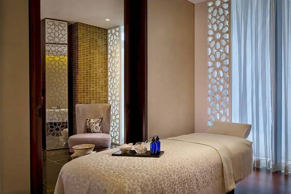 Wellnessbereich im Grand Hyatt Abu Dhabi Hotel mit Liege, Behandlungstisch und gemusterten Vorhängen.
