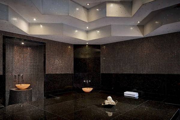 Innenansicht des Spa-Bereichs im Grand Hyatt Abu Dhabi Hotel mit schwarzen Fliesen und Holzbecken.