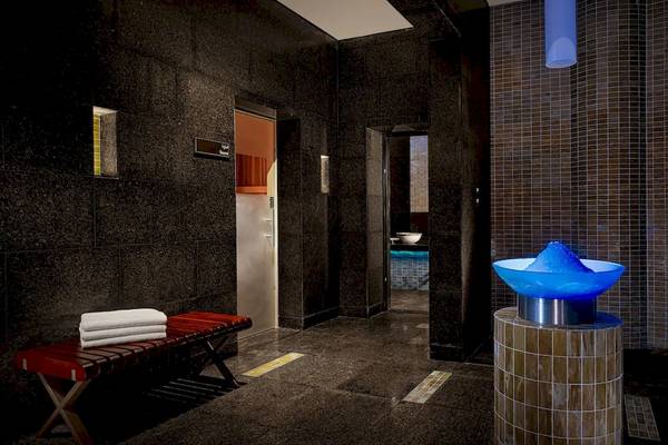 Innenbereich eines Badezimmers im Grand Hyatt Abu Dhabi Hotel mit einem roten Bank, schwarzen Wänden und einem blauen Wasserbrunnen.