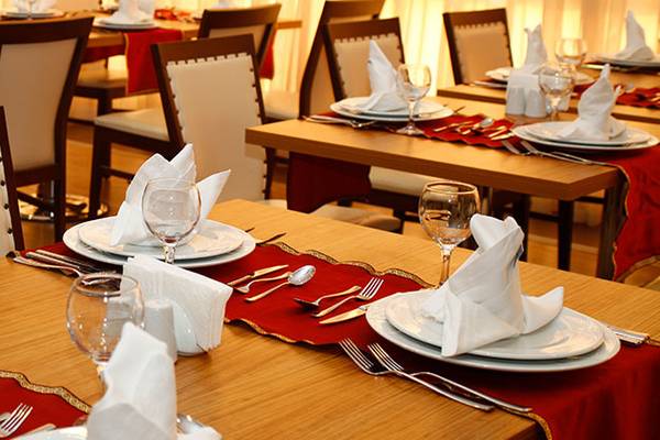 Gedeckte Tische im Restaurant des Cenger Beach Resort & Spa mit roten Tischläufern und weißen Servietten.
