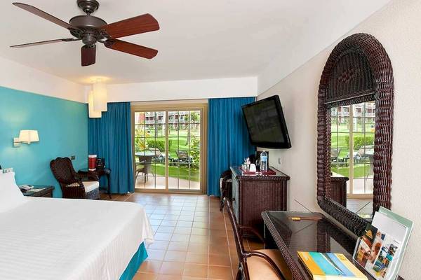 Hotelzimmer im Barcelo Bavaro Beach mit blauen Wänden, Doppelbett, Fernseher und Gartenblick.