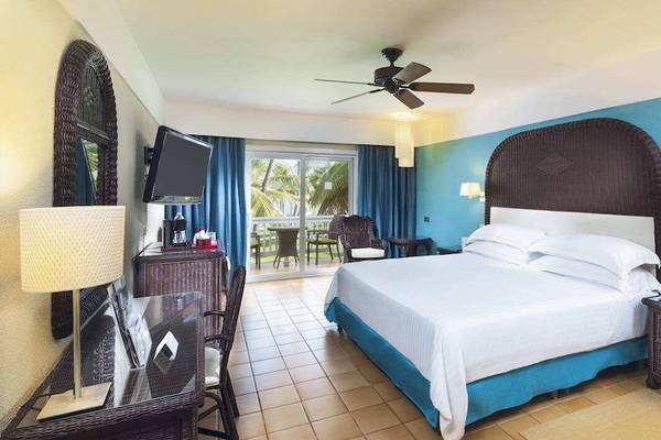 Hotelzimmer im Barcelo Bavaro Beach Hotel mit Bett, Fernseher und Balkon.