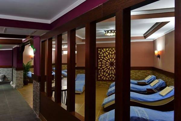 Innenansicht des Cenger Beach Resort & Spa mit Loungebereich und gepolsterten Liegen, gerahmt von dekorativ beleuchteten Wänden und Holzpaneelen.