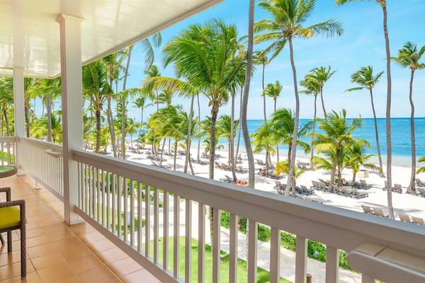 Balkon im Barcelo Bavaro Beach Hotel mit Tisch, Stuhl und Blick auf die Palmen und den Strand.