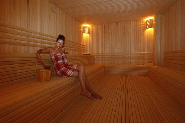 Eine Frau sitzt in einem Holzsaunaraum des Cenger Beach Resort & Spa.