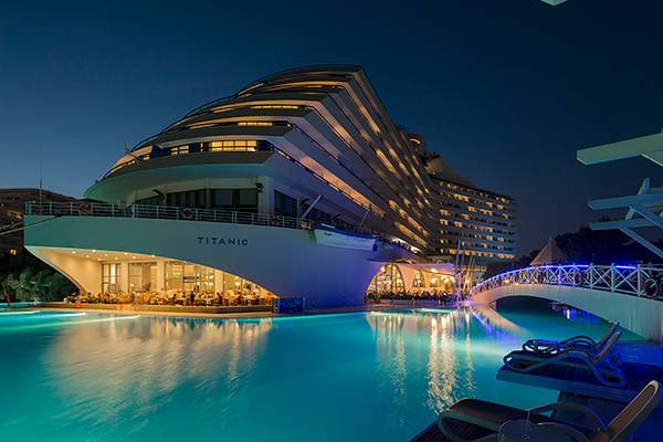 Außenansicht des Titanic Deluxe Lara Hotels mit Pool bei Nacht.