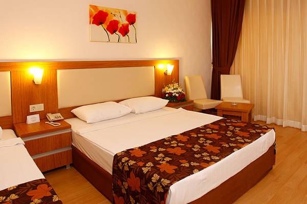 Hotelzimmer im Cenger Beach Resort & Spa mit zwei Betten, Kissen, Tischtelefon und Lampe.