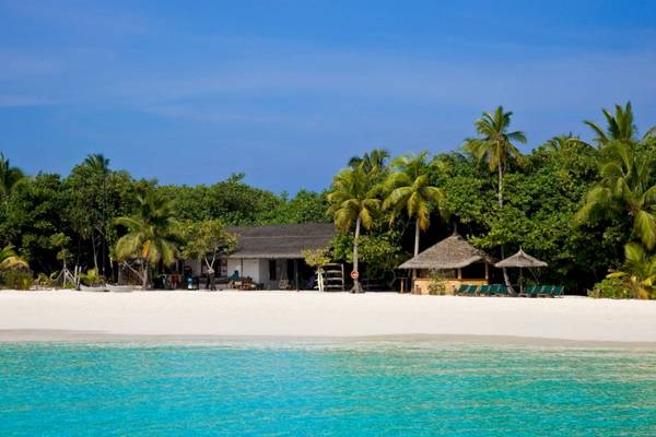 Reethi Beach Resort Strand mit Hotel, Palmen und Sonnenliegen