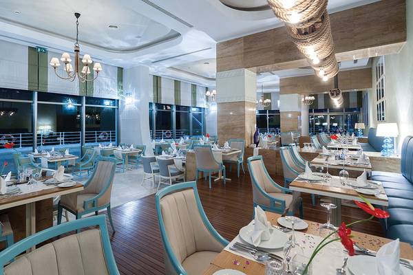 Innenansicht des Restaurants im Titanic Deluxe Lara Hotel mit blauen Stühlen und Tischen.
