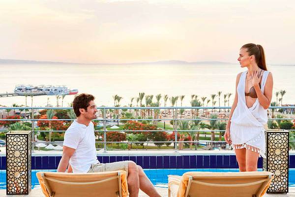 Paar am Pool im Steigenberger ALDAU Beach Hotel während des Sonnenuntergangs