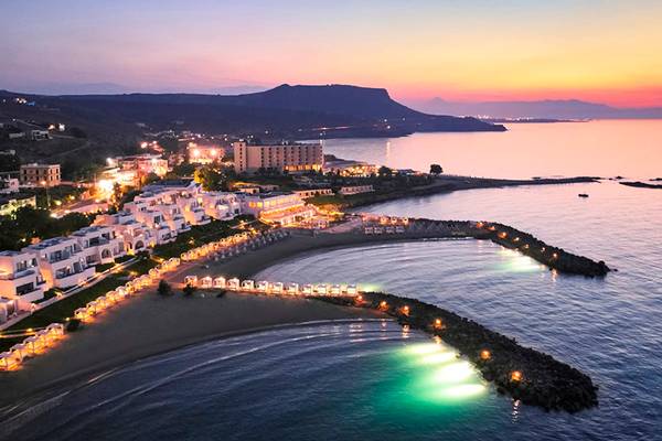 Knossos Beach Bungalows Suites Resort & Spa bei Sonnenuntergang mit beleuchteten Gebäuden und Strand