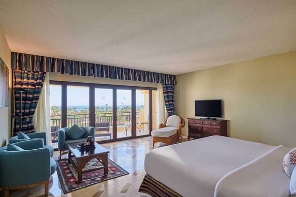 Hotelzimmer mit Balkon und Meerblick, großzügiges Zimmer mit zwei Betten, Wohnzimmermöbeln und Fernseher.