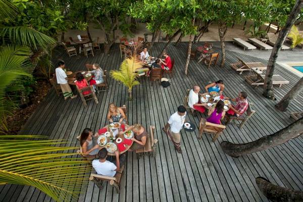 Gäste bei einer Mahlzeit auf einer hölzernen Terrasse im Reethi Beach Resort