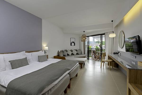 Modernes Hotelzimmer im Sunwing Kamala Beach mit Doppelbett, Sofa, Balkon und Fernseher.