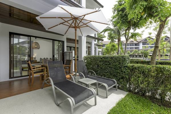 Zwei Lounger auf der Terrasse des Sunwing Kamala Beach Hotels mit einem Schirm und einem Tisch.