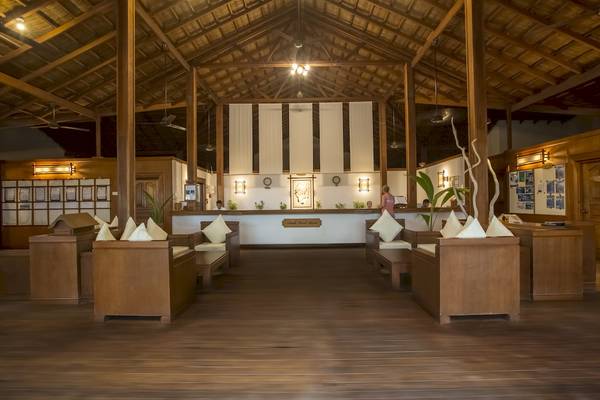 Innenansicht der Lobby im Reethi Beach Resort mit hölzernen Möbeln und Deckenventilatoren.