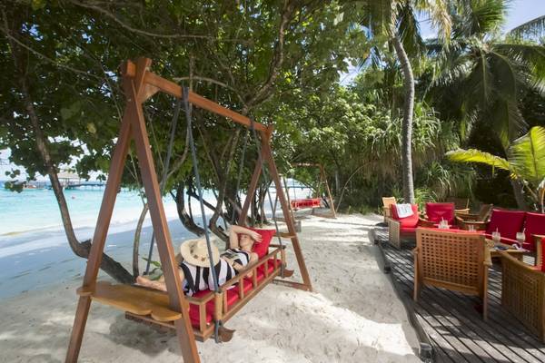 Personen entspannen auf einer Schaukel im Reethi Beach Resort.
