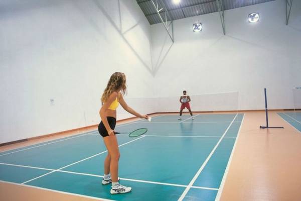 Im Reethi Beach Resort spielen zwei Personen Badminton auf einem Hallenplatz.