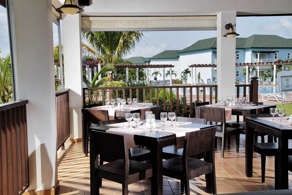Terrasse des Valentin Varadero El Patriarca Hotels mit Tischen und Stühlen und Blick auf das Meer.