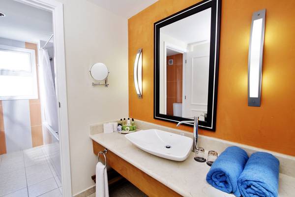 Badezimmer im Valentin Varadero El Patriarca Hotel mit Waschbecken, Spiegel und blauen Handtüchern.
