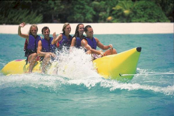Gäste des Reethi Beach Resorts auf einem Bananenboot im Wasser