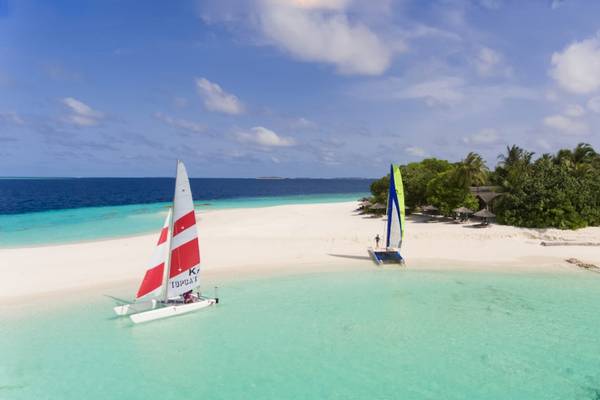 Luftaufnahme des Reethi Beach Resorts mit Segelbooten am Strand und grüner Vegetation.