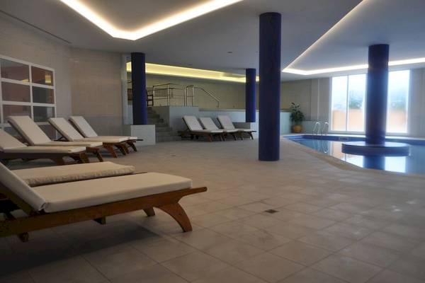 Innenpool-Lounge-Bereich im Bordoy Don Antonio Hotel mit weißen Liegen und blauen Säulen.