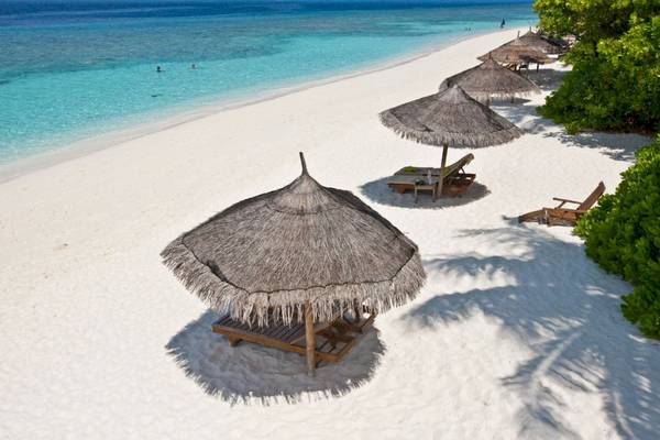 Sonnenliegen und Sonnenhute am Strand des Reethi Beach Resort
