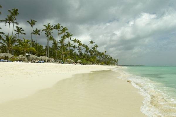 Strand des Grand Palladium Bavaro Suites Resort mit weißen Palmen und blauem Himmel